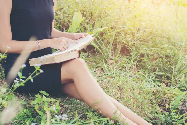 Avslappnad ung vacker kvinna läser en bok på gräsmattan med su — Stockfoto