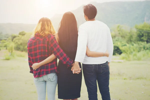 Triángulo amoroso, el hombre está abrazando a una mujer y él está cogido de la mano wi —  Fotos de Stock