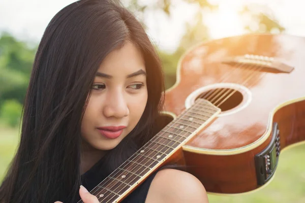 Bir gitar omzuna, doğa parkı su tutan güzel kadın