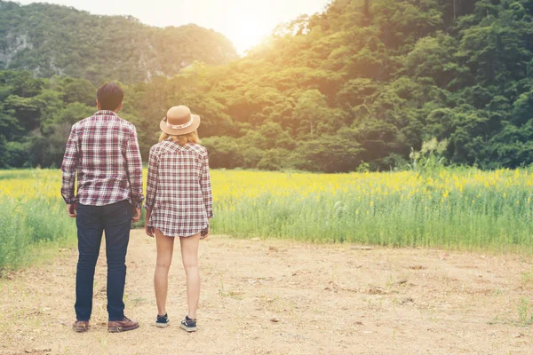 Jonge hipster paar nemen van een wandeling op mooie bloem veld. — Stockfoto