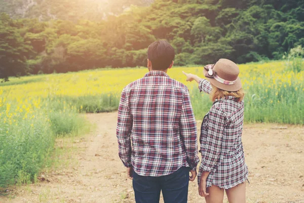 Jonge hipster paar nemen van een wandeling op mooie bloem veld. — Stockfoto