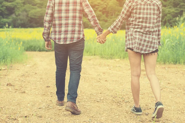 Joven pareja hipster dando un paseo por el hermoso campo de flores . —  Fotos de Stock