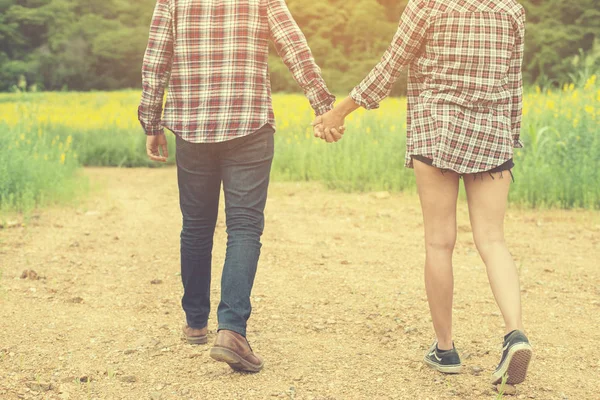 Jovem casal hipster dando um passeio no belo campo de flores . — Fotografia de Stock