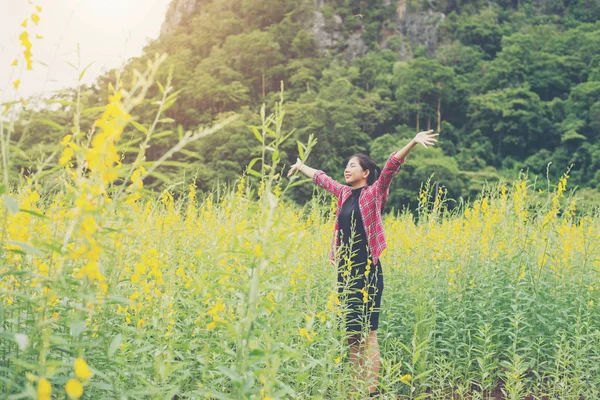 Jovem mulher bonita de pé no campo de flores prazer . — Fotografia de Stock