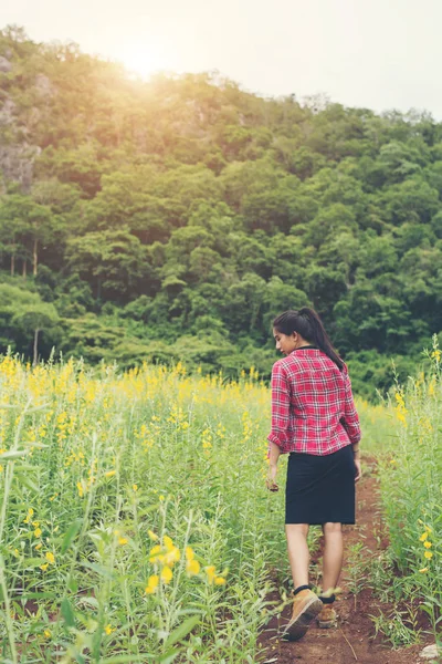 Jovem mulher bonita de pé no campo de flores prazer . — Fotografia de Stock