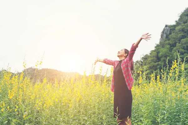 Young beautiful woman standing in the flower field enjoyment. — Stock Photo, Image