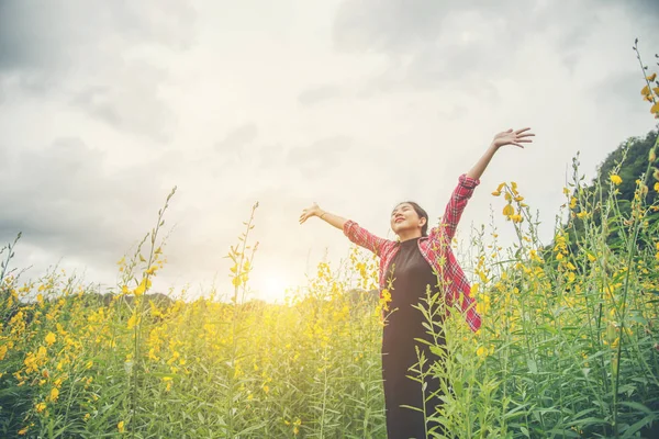 Ung vacker kvinna som står i blomma fältet åtnjutande. — Stockfoto