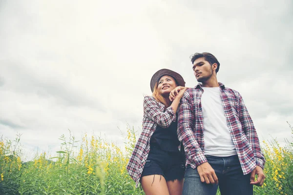 Jovens hipster casal amantes passeando em um campo de flores, rela — Fotografia de Stock