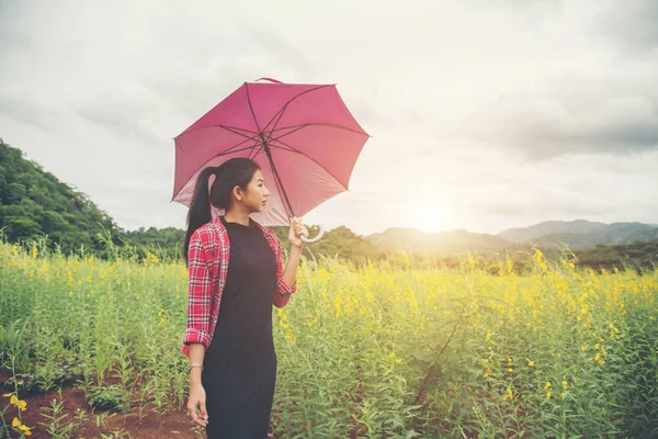 Jonge mooie vrouw met rode paraplu in gele bloem fiel — Stockfoto