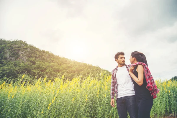 Young hipster couple relaxing in yellow flower field at summer. — Stock Photo, Image