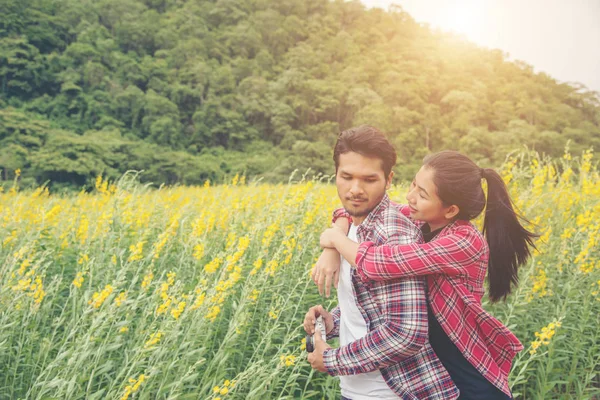 Joven pareja hipster relajándose en el campo de flores amarillas en verano . —  Fotos de Stock