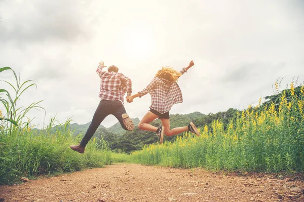 Молодая пара хипстеров в любви на открытом воздухе прыжки в желтый цветок Fi — стоковое фото