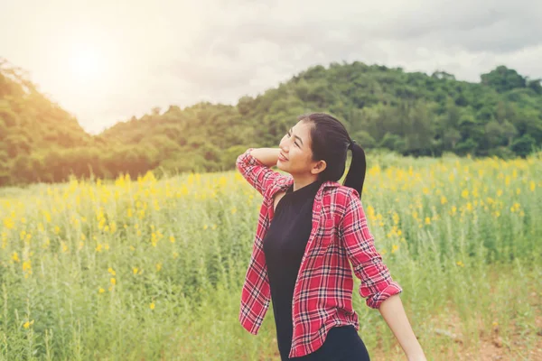 Gelukkig jongedame verhogen handen in gele bloem veld op zonsondergang — Stockfoto