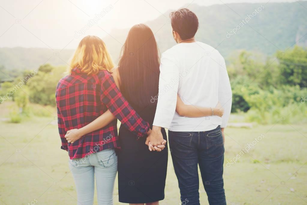Love triangle, Man is hugging a woman and he is holding hands wi