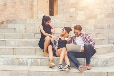 Grup merdiven konuşurken rel üzerinde oturmuş bir hipster öğrenci