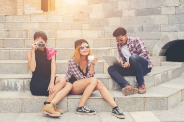 Grup merdiven konuşurken rel üzerinde oturmuş bir hipster öğrenci