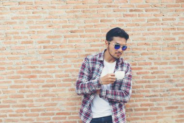 Kahve fincanı tutarak ve dış görev w arıyorum yakışıklı hipster genç adam