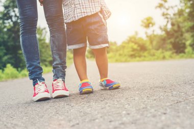 Anne küçük bebek çocuk evlat ayakları ile yolda yürürken 