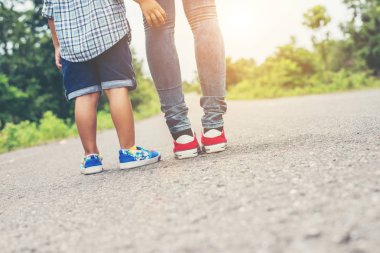 Anne küçük bebek çocuk evlat ayakları ile yolda yürürken 