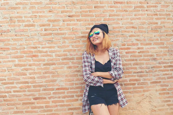 Junge hübsche Hipsterfrau, die gegen Ziegelwand posiert — Stockfoto