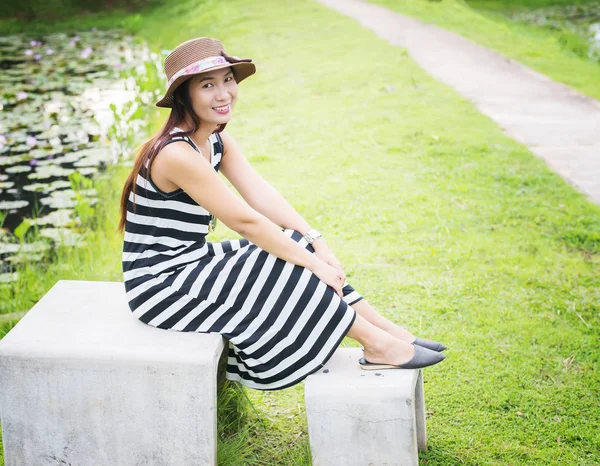 Jovem bela mulher sentada no banco no parque verde . — Fotografia de Stock