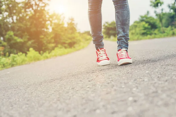 Piedi donna con scarpe da ginnastica rosse che camminano sul ciglio della strada . — Foto Stock