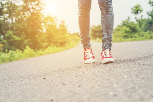 Kvinna fötter med röda sneaker skor går på vägarna. — Stockfoto