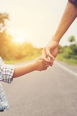 Anne oğlunun elini açık havada yürürken yaz aylarında tutuyor.