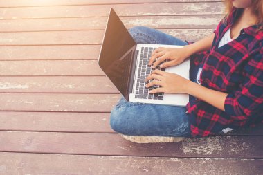 Genç hipster pier göl kenarında oturmuş, rahatlatıcı yazarak dizüstü eller