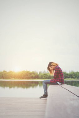 İskelede üzüntü ile oturan üzgün hipster kadın.