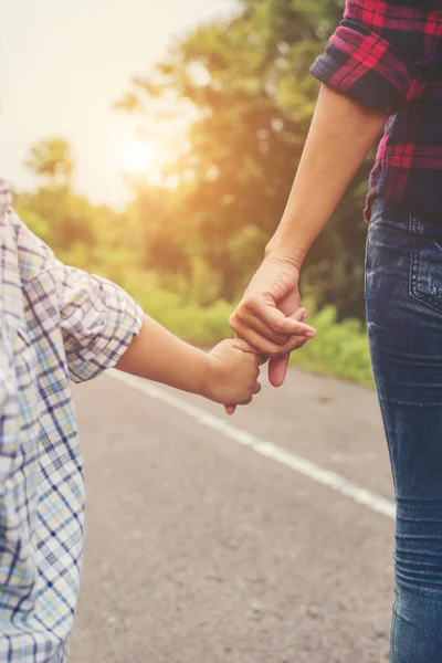 Anne oğlunun elini açık havada yürürken yaz aylarında tutuyor.