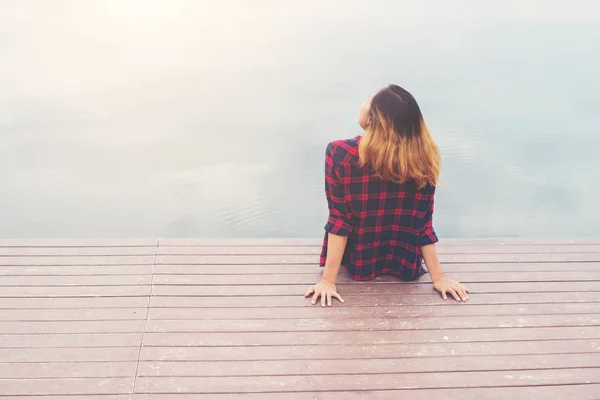 Costas de jovem hipster mulher sentado no cais, relaxante desfrutar w — Fotografia de Stock