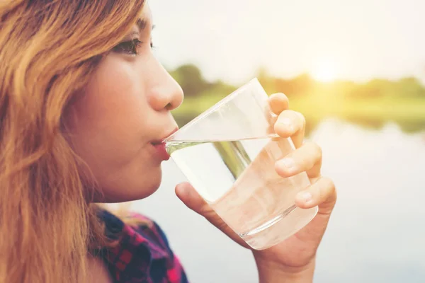 Jonge mooie hipster vrouw drinkwater staande op de pier, r — Stockfoto