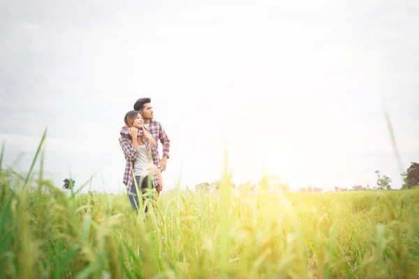 Joven pareja hipster de pie en el campo señalando la mirada hacia el —  Fotos de Stock