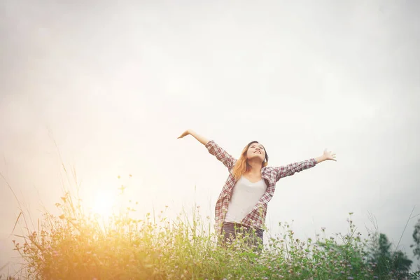 Jovem mulher hipster bonita em um campo de flores ao pôr do sol. Libertado. — Fotografia de Stock