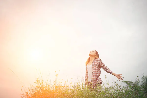 Joven mujer hipster hermosa en un campo de flores al atardecer. Liberado. — Foto de Stock