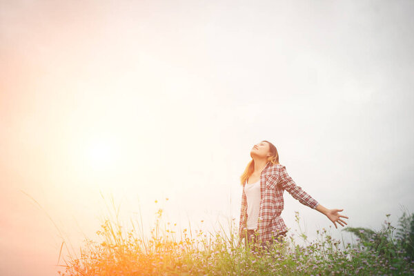 Young beautiful hipster woman in a flower field at sunset. Freedom enjoying with nature.
