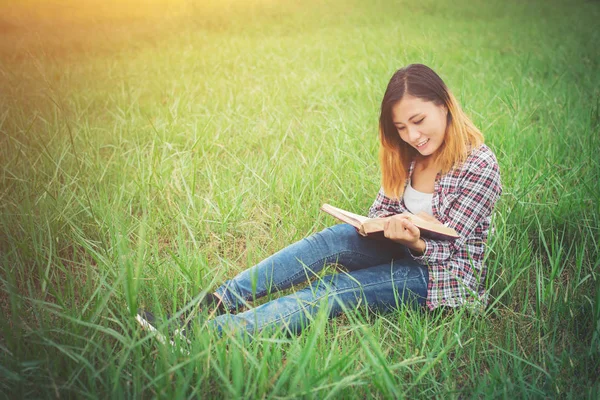 Ung vacker hipster sittande läsebok på gräsmark. — Stockfoto