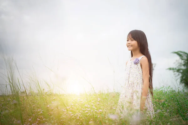 Маленька мила азіатська дівчинка, що йде серед фіолетового квіткового поля, fr — стокове фото