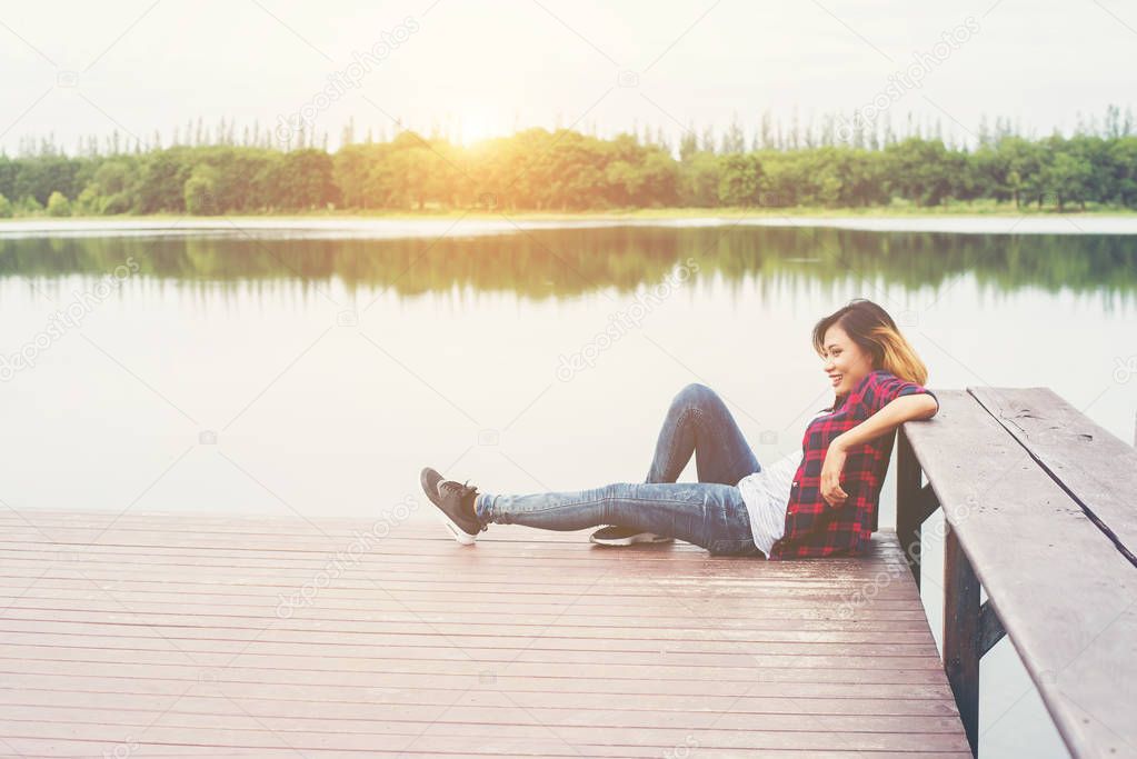 Young hipster woman sitting on wooden pier, Relaxing.