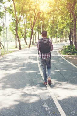 bir adam zaman yan yolda yürürken sırt çantası ile arka görünüme git