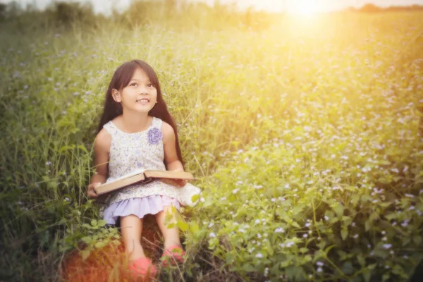 Piccolo carino asiatico ragazza lettura libro a natura . — Foto Stock