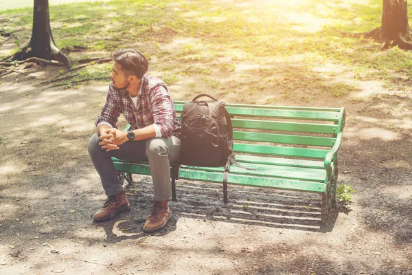 Jonge hipster man met rugzak naast zittend op een houten bankje — Stockfoto