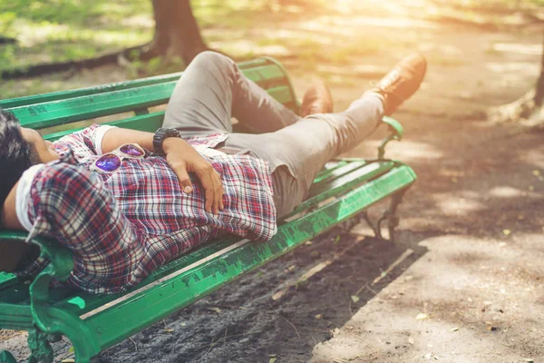 Mladí bokovky muž ležící na zelené lavičce, koukal. — Stock fotografie