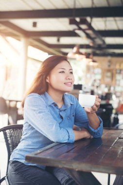 Kafede bir fincan kahve içen güzel genç bir kadın.. 