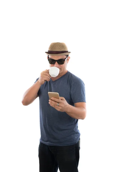 Unga hipster mannen tittar på sin smarta telefon och dricka kaffe — Stockfoto