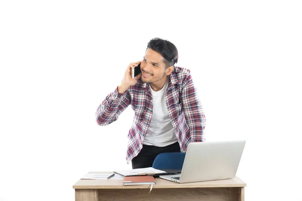 Jovem empresário falando no telefone enquanto trabalhava no laptop em de — Fotografia de Stock