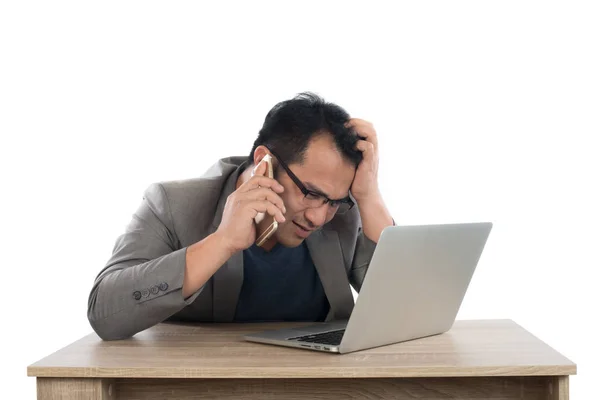 Стрессовый бизнесмен разговаривает по телефону с ноутбуком сидя — стоковое фото