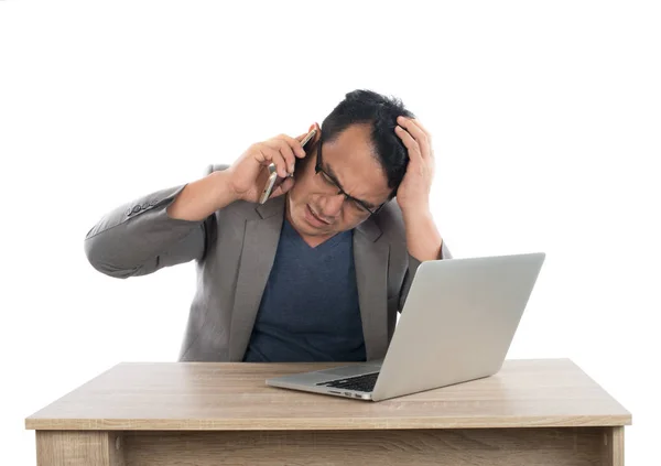 Стрессовый бизнесмен разговаривает по телефону с ноутбуком сидя — стоковое фото