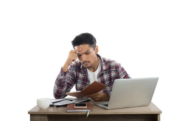 Pensativo joven sosteniendo la pluma mirando el bloc de notas mientras está sentado —  Fotos de Stock